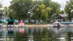 A lakeside property with a dock, boats, and a row of cabins. - 3BR Townhome | Beach Access & Pontoon Rentals (Nisswa)