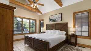 A bedroom with a wooden bed, large windows, a ceiling fan, and a painting on the wall. - 3BR Townhome | Beach Access & Pontoon Rentals (Nisswa)