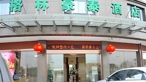A hotel entrance with a sign in Chinese characters, a red lantern, and a car parked in front. - Greentree Inn Jiaxing Tongxiang Tudian Express Hotel (Jiaxing)