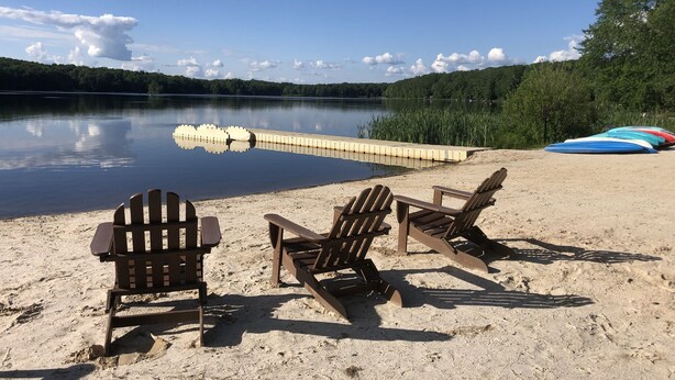 A lakeside beach with three Adirondack chairs and a rowboat. - Newly updated, great for multiple families up to 12 & pets; read reviews! (Clifton Township)