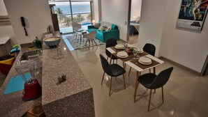 Una cocina moderna con encimeras de granito, una licuadora integrada y un comedor con una mesa preparada para cuatro.