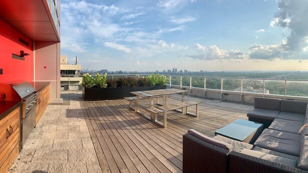 Terraza en la azotea con zona de barbacoa, mobiliario y vistas del horizonte urbano.