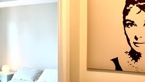 Un dormitorio con cama, mesita de noche y una obra de arte colgada en la pared.