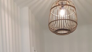 Un couloir avec un panier tressé accroché au mur, une porte et un luminaire suspendu.
