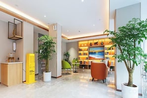 Una hall moderna con reception, area salotto e libreria piena di libri.
