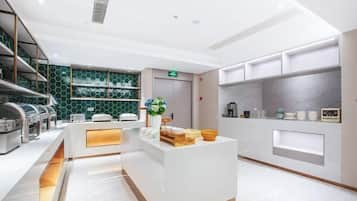 Un moderno vestíbulo de hotel con una recepción, una estación de café y un área de descanso.