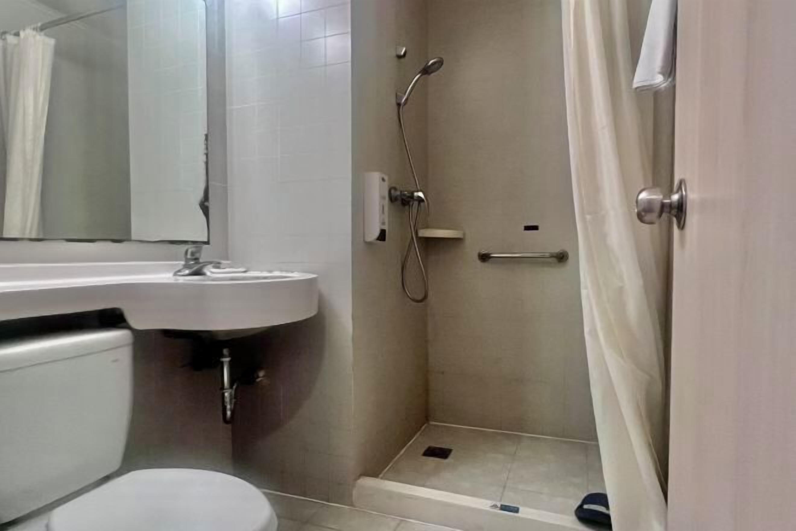 Ein Badezimmer mit Toilette, Waschbecken, Dusche und Spiegel.