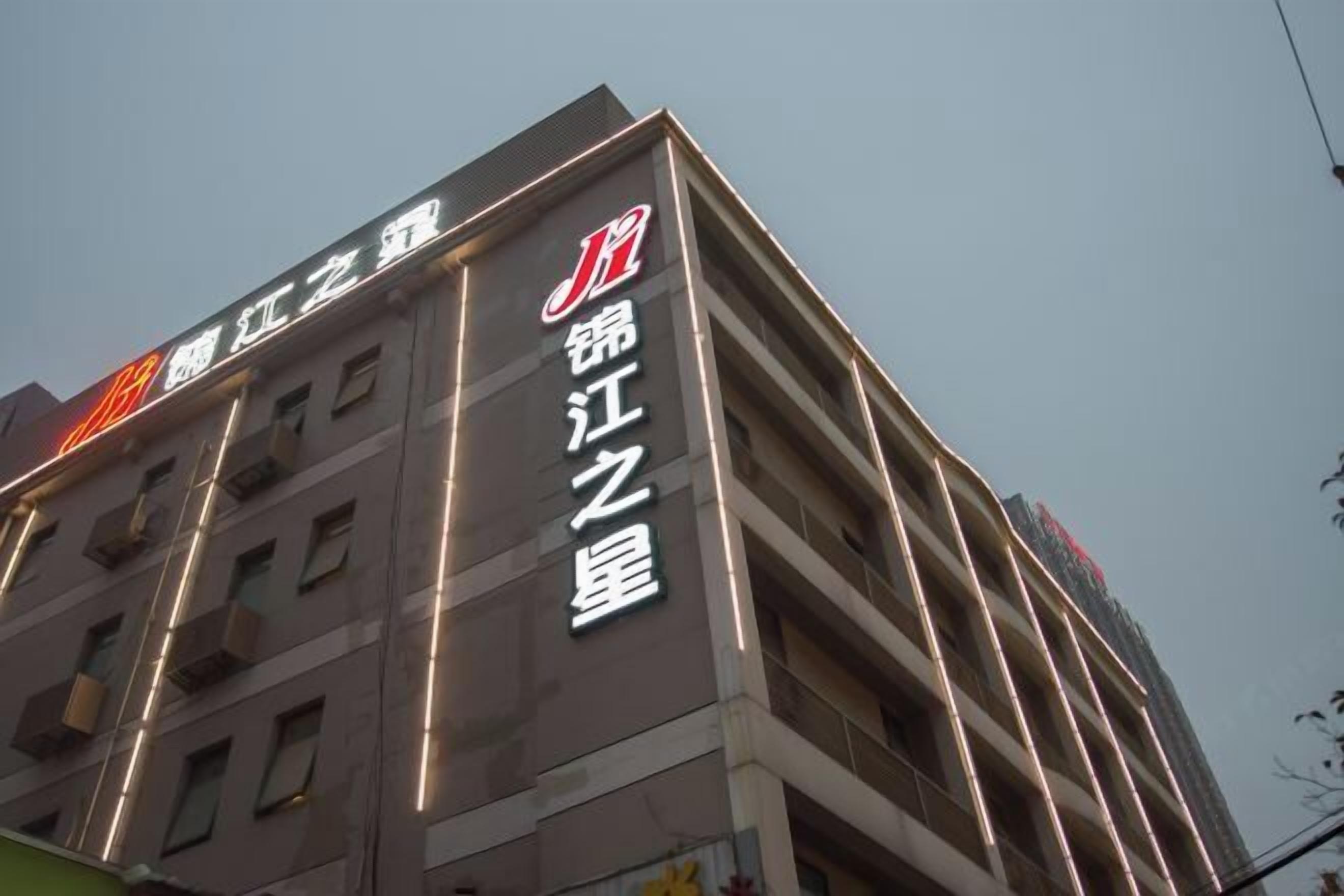 A building with illuminated signage reading "锦江之星" and "江江之星".