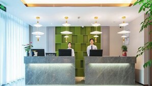 A reception area with two receptionists behind a marble counter, green wall panels, and pendant lighting. - Jinjiang Inn (Wuhan Lingjiaohu Wanda) (Wuhan)