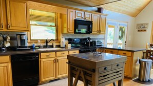 A modern kitchen with wooden cabinets, a stainless steel sink, and a built-in microwave. - Misty Mountain Cabin w/ gorgeous views   (Piney Creek)
