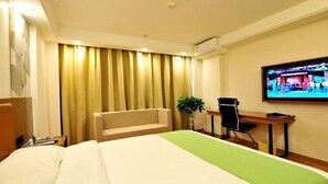 A hotel room with a bed, a desk, a chair, a television, and a curtain. - Greentree Inn Haikou City Wuzhishan Road (Haikou)