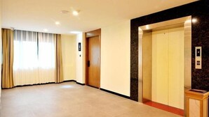 A hotel corridor with a wooden door, an elevator, and a marble wall. - Greentree Inn Haikou City Wuzhishan Road (Haikou)