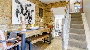 Un muro de piedra, un banco de madera, una mesa de comedor, una silla y una escalera.
