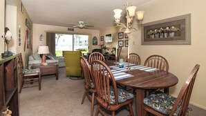 A dining area with a wooden table and chairs, a chandelier, and a framed picture on the wall.