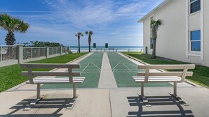 A boardwalk with benches, palm trees, and a view of the ocean.
