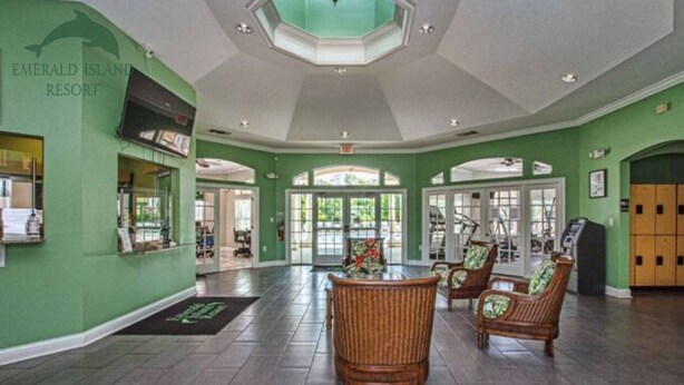 A spacious lobby with green walls, wicker chairs, and a large glass door leading outside. - Dreams come true (Kissimmee)