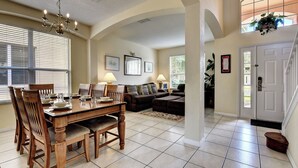 A spacious living area with a dining table set for four, a sofa, and a staircase leading to another level. - Dreams come true (Kissimmee)