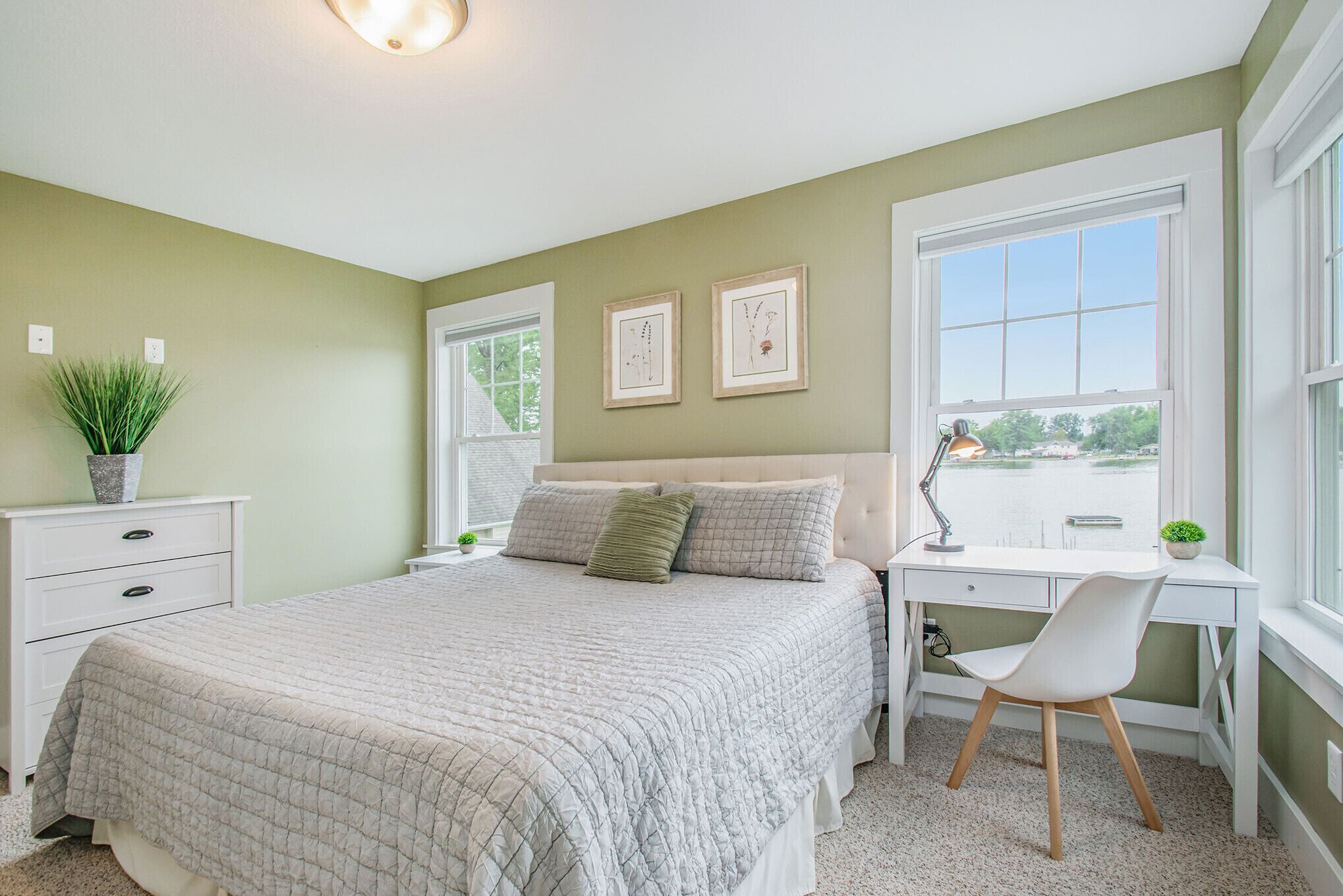 A bedroom with a bed, a desk, a chair, and a window.