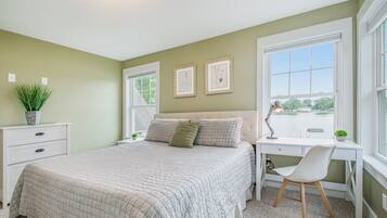 A bedroom with a bed, a desk, a chair, and a window.