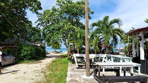 A beachside cafe with outdoor seating, a view of the ocean, and a palm tree. - Drifters at One Mile - Hostel (Negril)