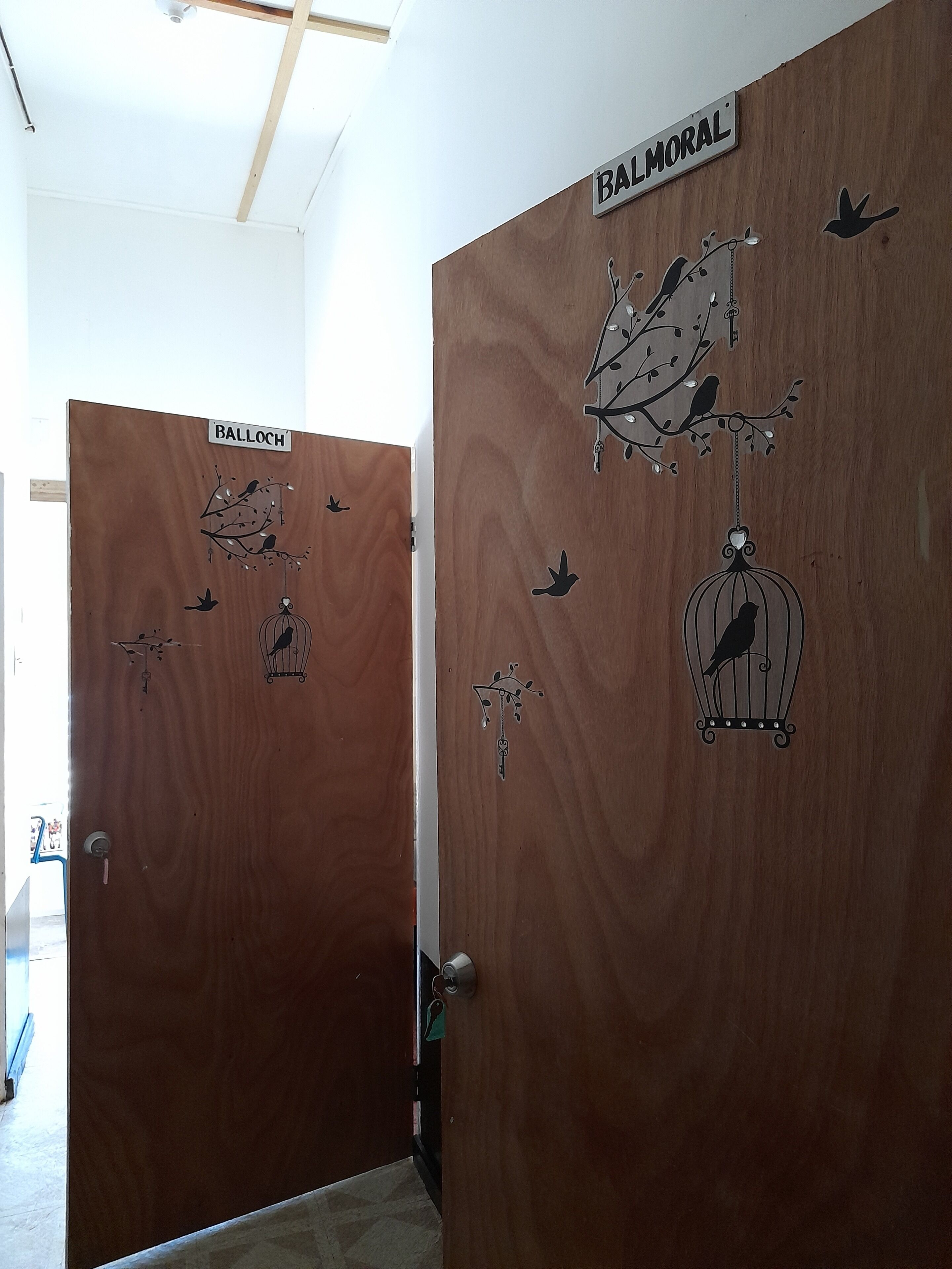 Two wooden doors with bird and branch decals, labeled "BALLOCH" and "BALMORAL".