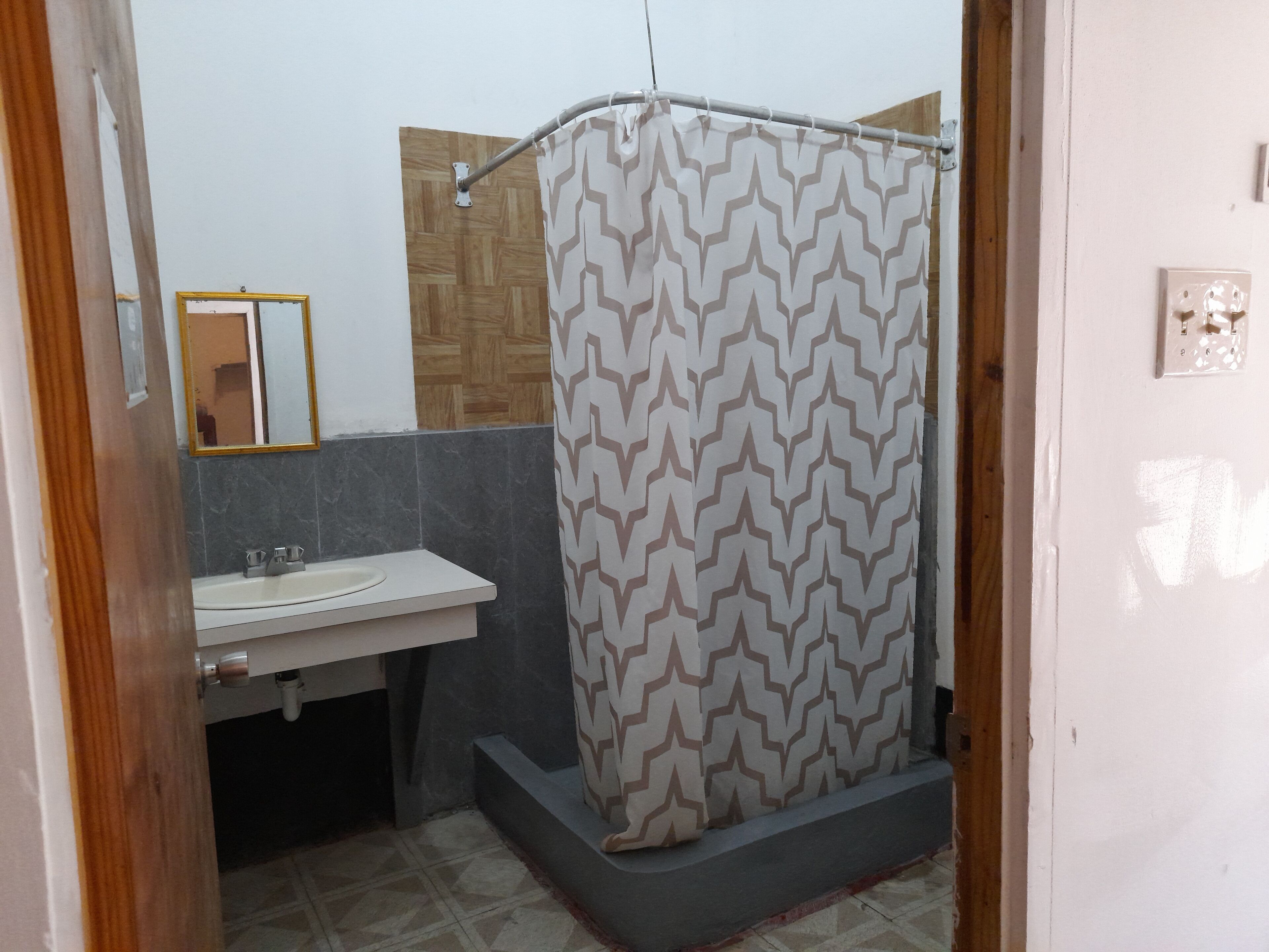 A bathroom with a shower curtain, a sink, and a mirror.
