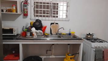 Una cocina con estufa a gas, lavamanos y extintor en la pared.