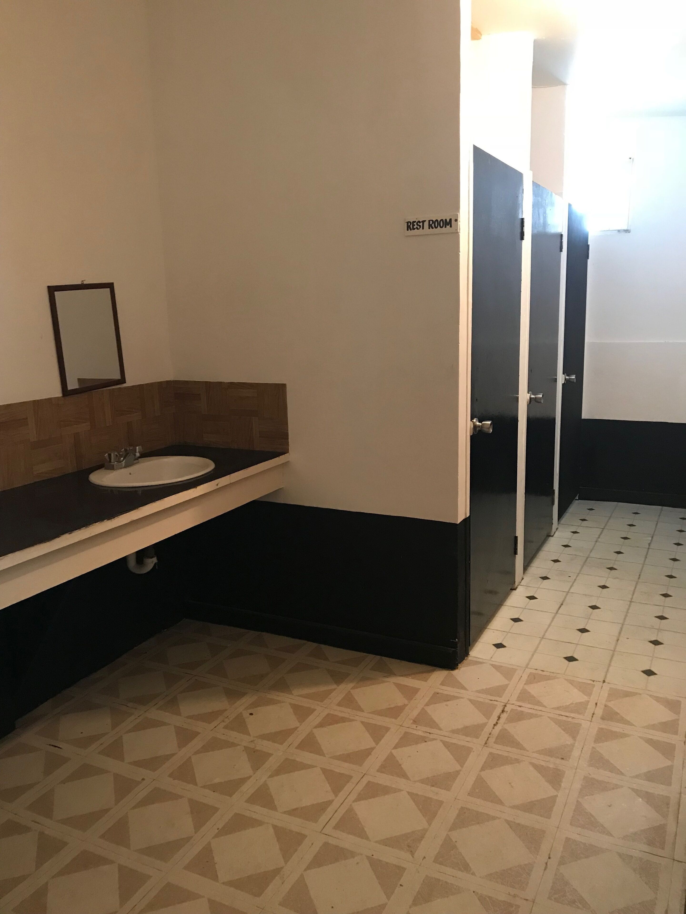 A restroom with a sink, mirror, and a sign indicating it is a rest room.
