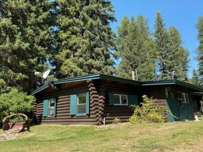 Surrounded by lush greenery, this cabin offers a cozy retreat with a front porch and chimney.