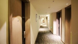 Un pasillo de hotel con puertas de madera, suelo alfombrado y un largo corredor que lleva a una habitación.