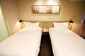 A hotel room with two beds, a headboard with artwork, bedside lamps, a nightstand with a phone, and a small table. - Jinjiang Inn Select (Qingdao International Exhibition Center Miaoling Road) (Qingdao)
