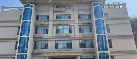 A multi-story hotel with a central entrance and a balcony on the second floor.