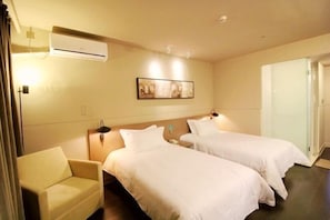 A hotel room with two beds, a sofa, an air conditioning unit, a painting on the wall, and a door. - Jinjiang Inn Select (Qingdao International Exhibition Center Miaoling Road) (Qingdao)