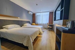 Habitación de hotel con dos camas, un escritorio, una silla y una ventana con cortinas.