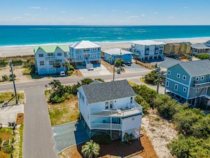A coastal residential area with beachfront properties, including a house with a balcony and a two-story building with a green roof. - The Channel Marker | Ocean to Sound Views! (Topsail Beach)