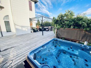 A wooden deck with a hot tub, outdoor furniture, and a pergola. - Spacious 3BR Retreat w/ Hot Tub Ravine | Sleeps 9 (Edmonton)