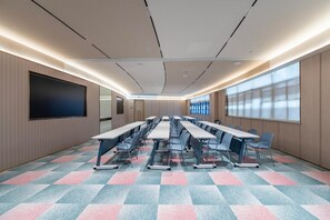 A conference room with a large table, chairs, a screen, and a patterned carpet.