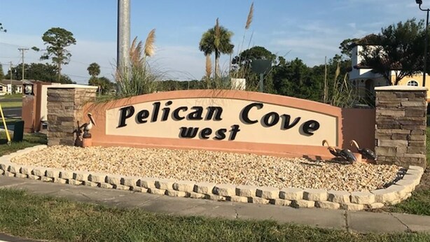 Skilt for Pelican Cove West med et anlagt område foran.