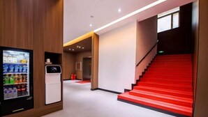 A modern hotel lobby with a vending machine, a staircase with red steps, and a clean, minimalist design. - Jinjiang Inn (Changchun Railway Station) (Changchun)