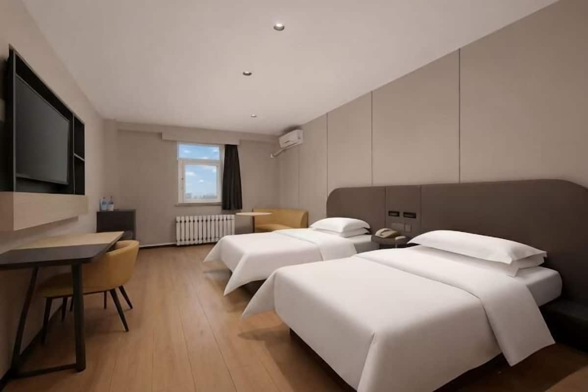A hotel room with two beds, a desk, a chair, a TV, and a window with a view.