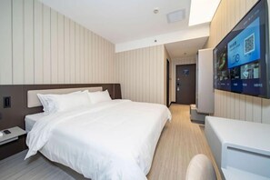 Une chambre d’hôtel moderne dotée d’un grand lit, d’un téléviseur à écran plat fixé au mur et d’un petit bureau avec une chaise.