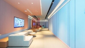 Un intérieur moderne avec un long couloir, des espaces de détente et un écran de télévision fixé au mur.