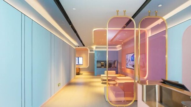 Un hall d’hôtel moderne avec un long couloir, un espace salon et un comptoir d’accueil.