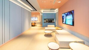 Un hall d’hôtel moderne avec un long couloir, des espaces de détente et un comptoir d’accueil.