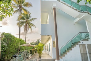 A modern building with a staircase, a covered outdoor area, and lush greenery.