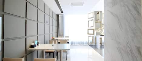A modern interior with a long dining table, chairs, and a marble wall.