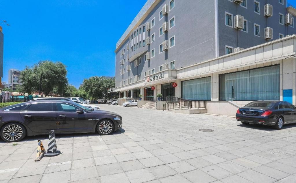Um edifício moderno com fachada plana, várias janelas e entrada protegida por portão.