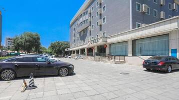 Um edifício moderno com fachada plana, várias janelas e entrada protegida por portão.