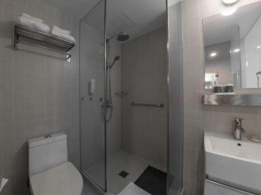 Un baño moderno con cabina de ducha de vidrio, inodoro y lavabo con espejo.