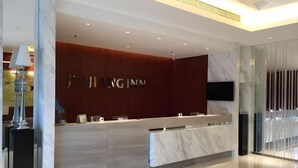 A modern hotel reception area with a marble counter, a TV mounted on the wall, and a glass partition. - Jinjiang Inn Select (Beijing Wukesong) (Beijing)